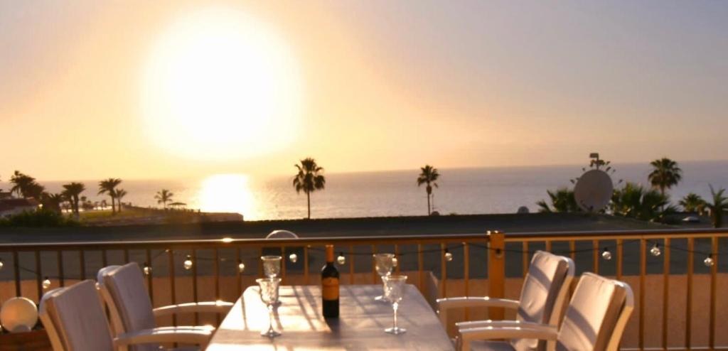 - une table avec une bouteille de vin et des chaises sur le balcon dans l'établissement Ocean View, Große Sonnenterrasse, Meerblick, Tamara Komplex, Teneriffa Süd, Los Gigantes, 500m Strand, Pool, 300m zum Ort, ruhig, à Acantilado de los Gigantes