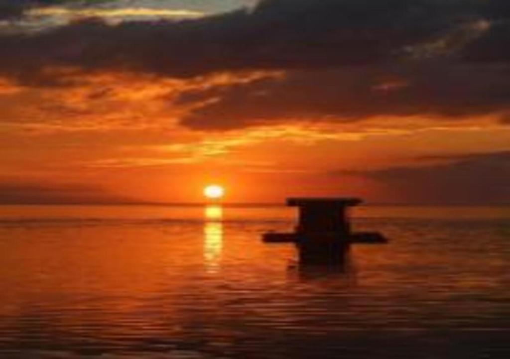 a cross in the water with a sunset in the background at Beach Road Apartments in Matabungkay