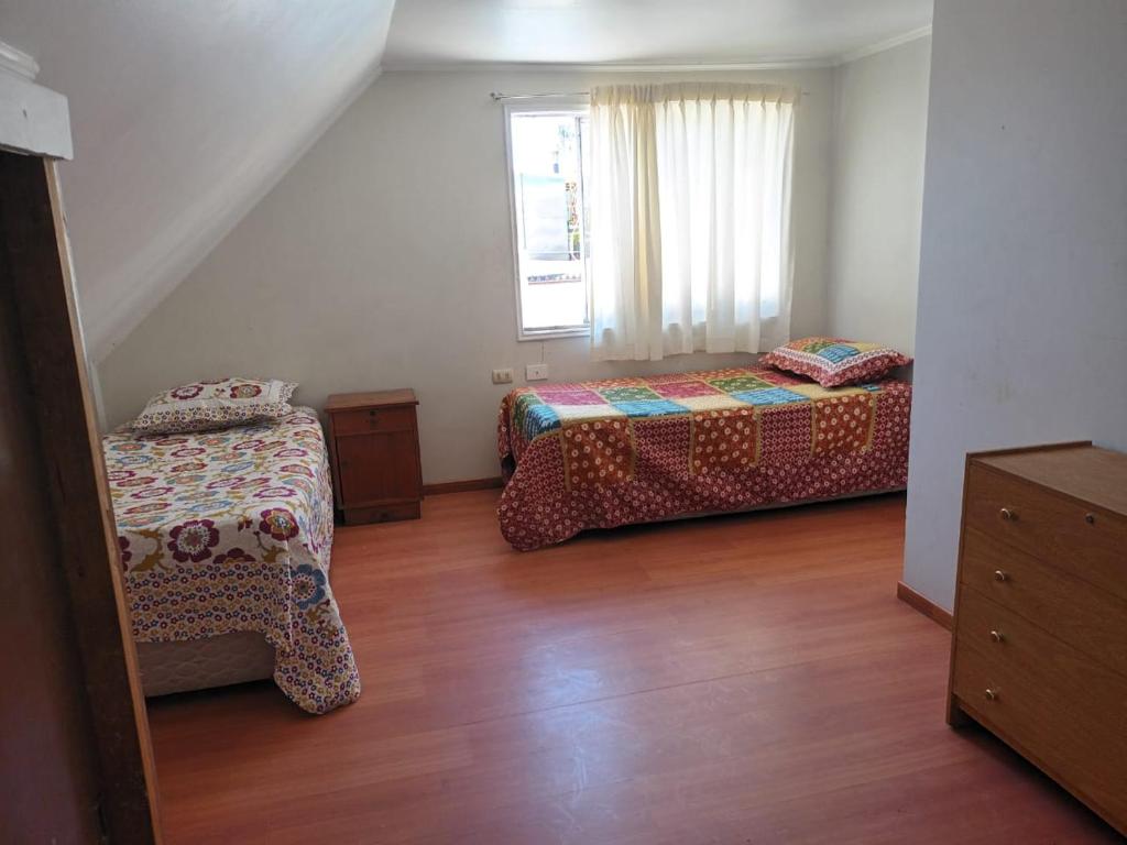 a bedroom with two beds and a window at Hospedaje JM in Chillán
