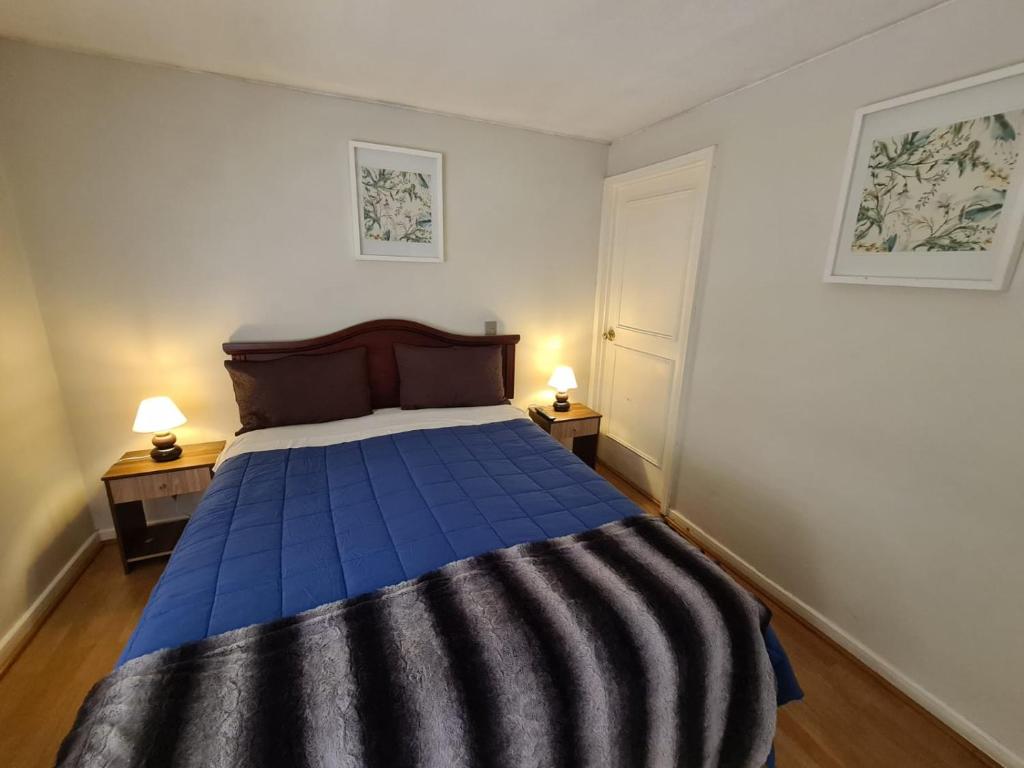 1 dormitorio con 1 cama azul y 2 mesitas de noche en Avenida Suites, en Santiago