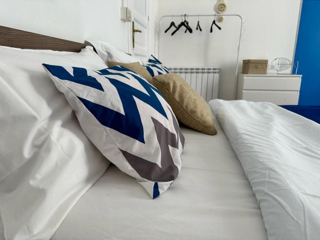 Una cama blanca con almohadas azules y blancas. en Via Zara en Palermo