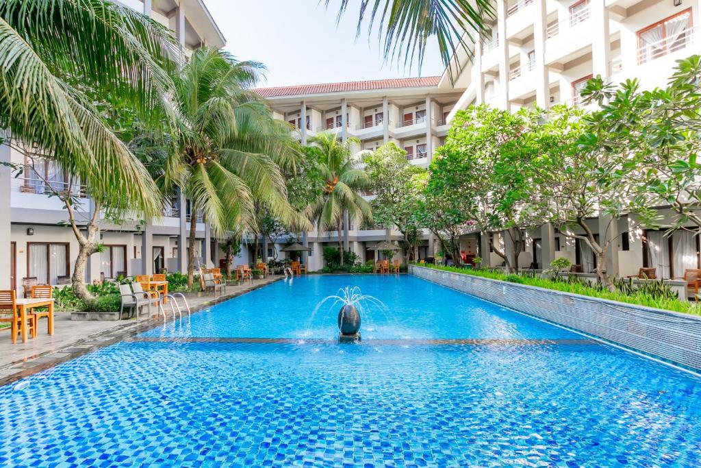 a pool in the middle of a building with palm trees at Lombok Garden Hotel in Mataram