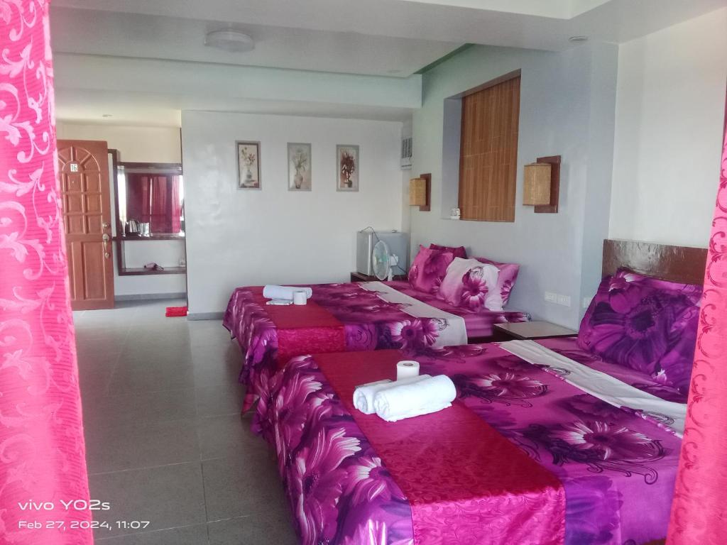 a room with four beds with pink sheets at Bellevue Resort in Puerto Galera