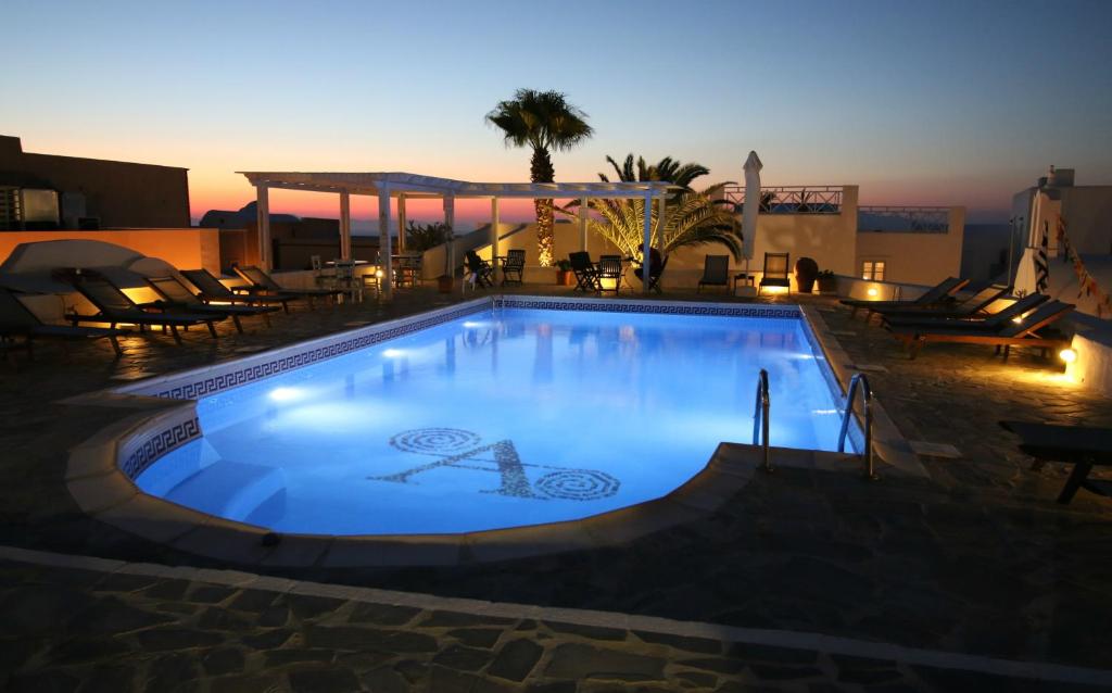 a large swimming pool with a sunset in the background at Aethrio Sunset Village - Oia in Oia