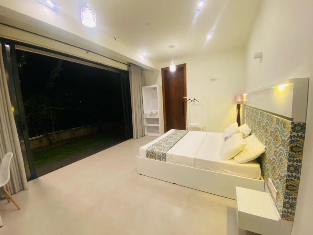 ein Schlafzimmer mit einem Bett und einem großen Fenster in der Unterkunft Amelia Misty Hills in Kandy