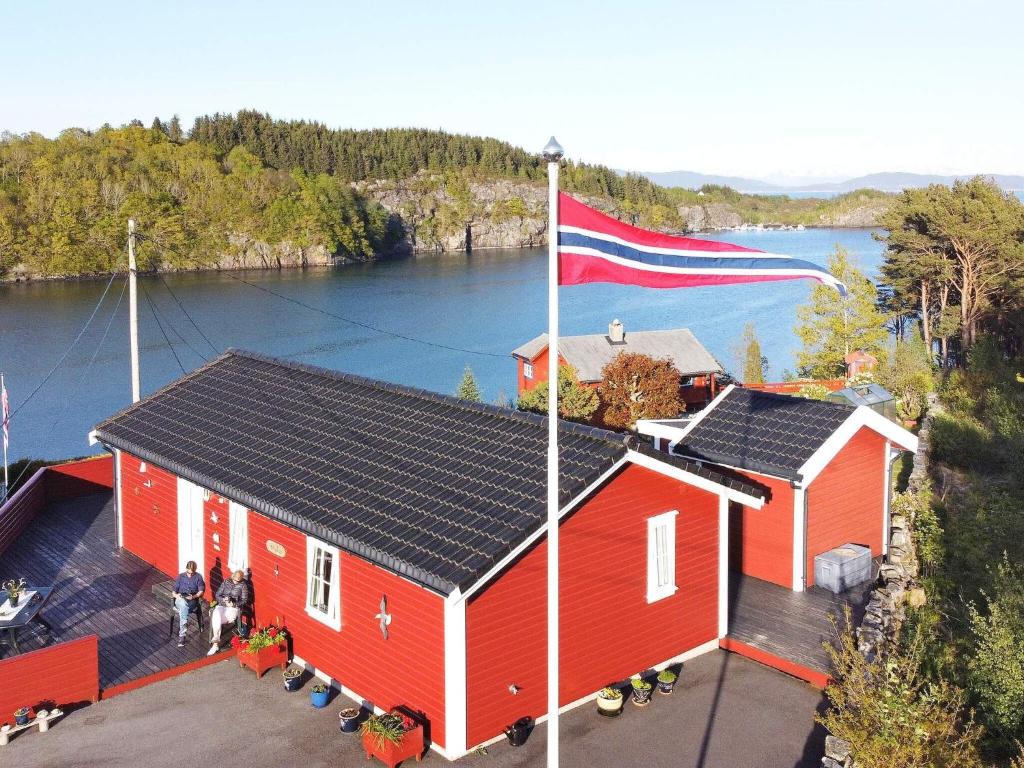 una casa roja con una bandera frente a un lago en Holiday home KLOKKARVIK II, en Klokkarvik