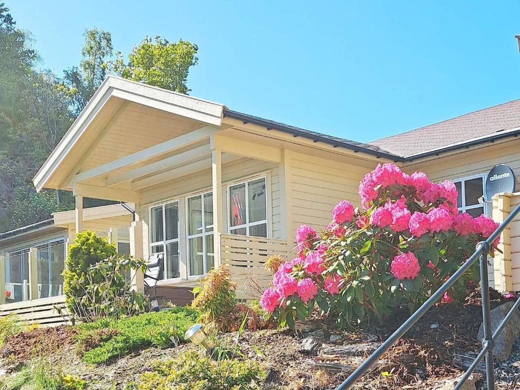 une petite maison avec des fleurs roses devant elle dans l'établissement 8 person holiday home in lyngdal-By Traum, à Lyngdal