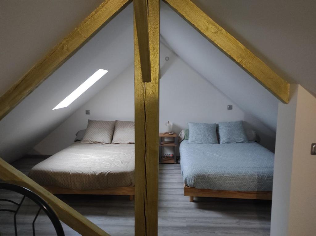 a attic bedroom with two beds in a attic at maison luxe cléo aeroport tillé 4 a 5 personnes in Tillé