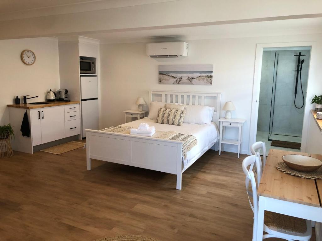 a bedroom with a white bed and a kitchen at The White Room in Yeppoon