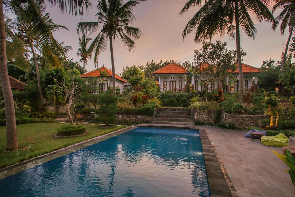 a house with a swimming pool and palm trees at De Casa Ananda Nusa Penida in Nusa Penida