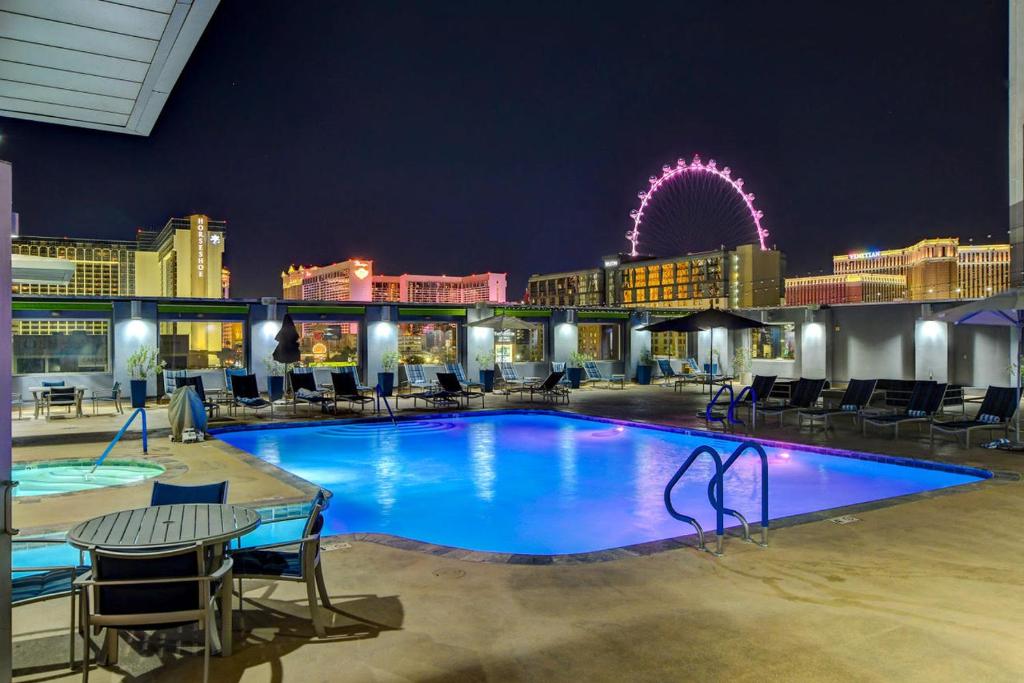 a large swimming pool with a ferris wheel in the background at Diligence at The Platinum - NO Resort Fees and Free Parking in Las Vegas