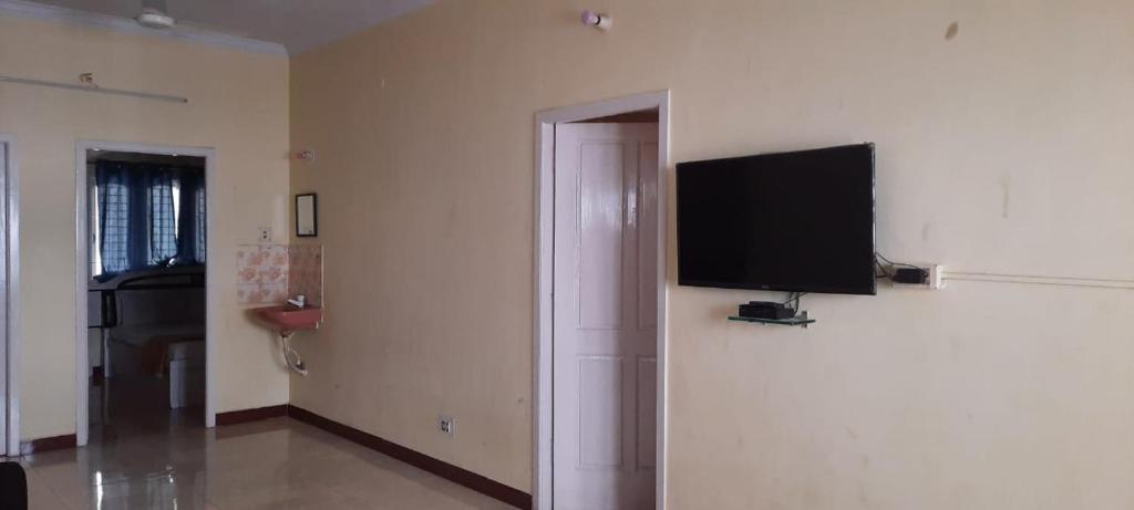 ein Wohnzimmer mit einem Flachbild-TV an der Wand in der Unterkunft Sathya Service Apartment in Chennai