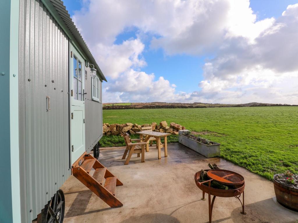 a patio with a table and a view of a field at Lower Trewern Shepherds Hut in Penzance