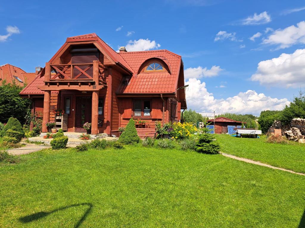 dom z czerwonym dachem na zielonym trawniku w obiekcie Dom drewniany z ogrodem w Szczecinku