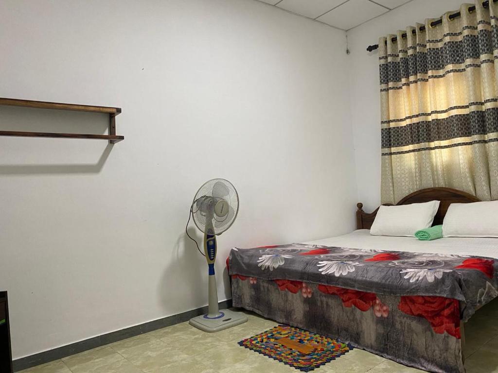 a bedroom with a bed with a fan next to it at Green willa in Badulla