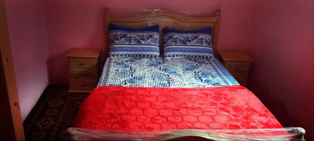 ein Bett mit einer roten und blauen Bettdecke darauf in der Unterkunft Hermanos ketama hotil in Tlata Ketama