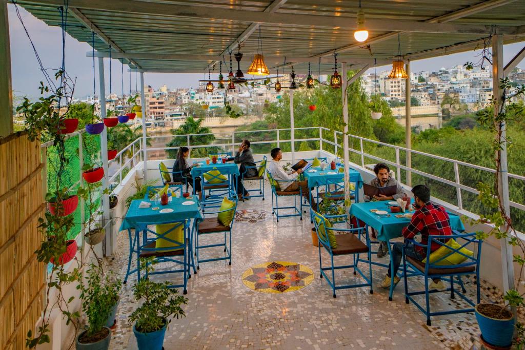 a group of people sitting at tables on a balcony at Soham Haveli - A Lake Facing Stay in Udaipur in Udaipur