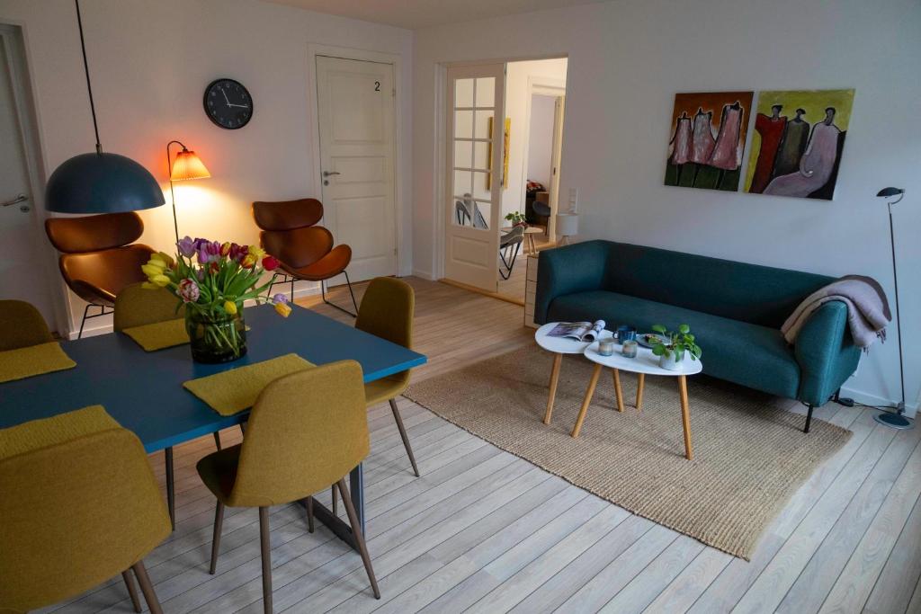 een woonkamer met een blauwe bank en een tafel bij Hyggelig byhus i stueplan med solrig gårdhave in Svendborg