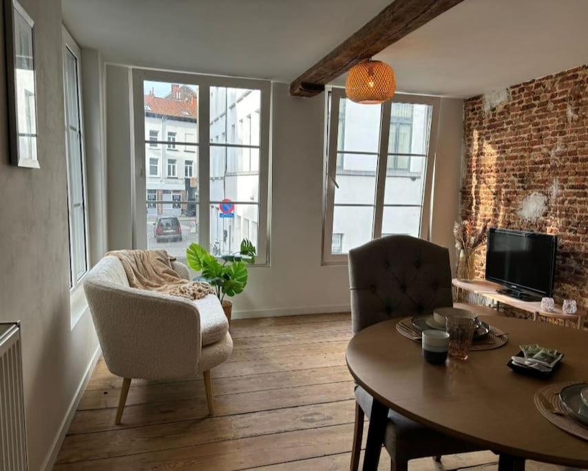 ein Wohnzimmer mit einem Tisch, Stühlen und einem TV in der Unterkunft Charming Bohemian central app in Antwerpen