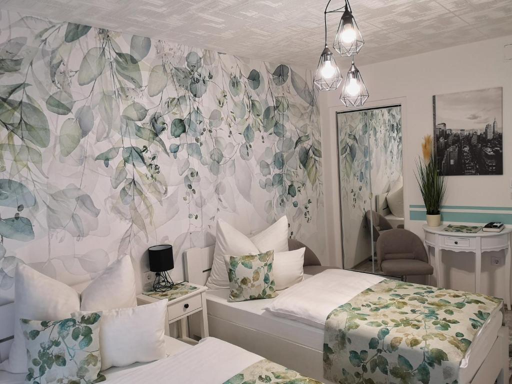 a bedroom with two beds and a floral wall at Anna Panzió in Herend