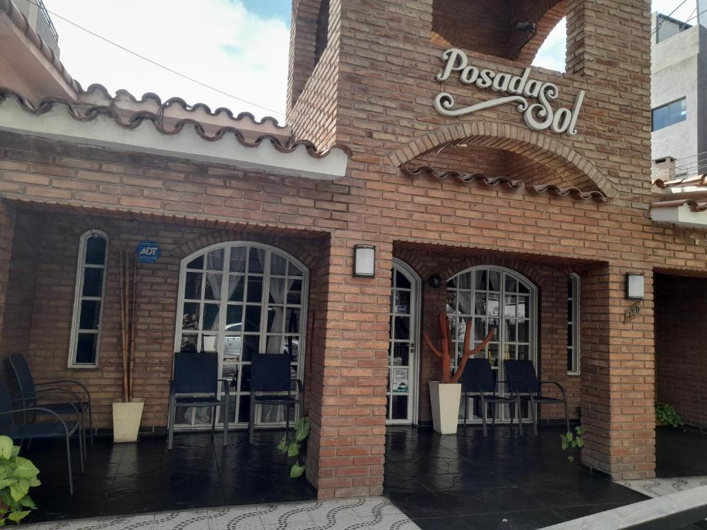 un edificio de ladrillo con mesas y sillas al aire libre en Hotel Posada Sol en Villa Carlos Paz