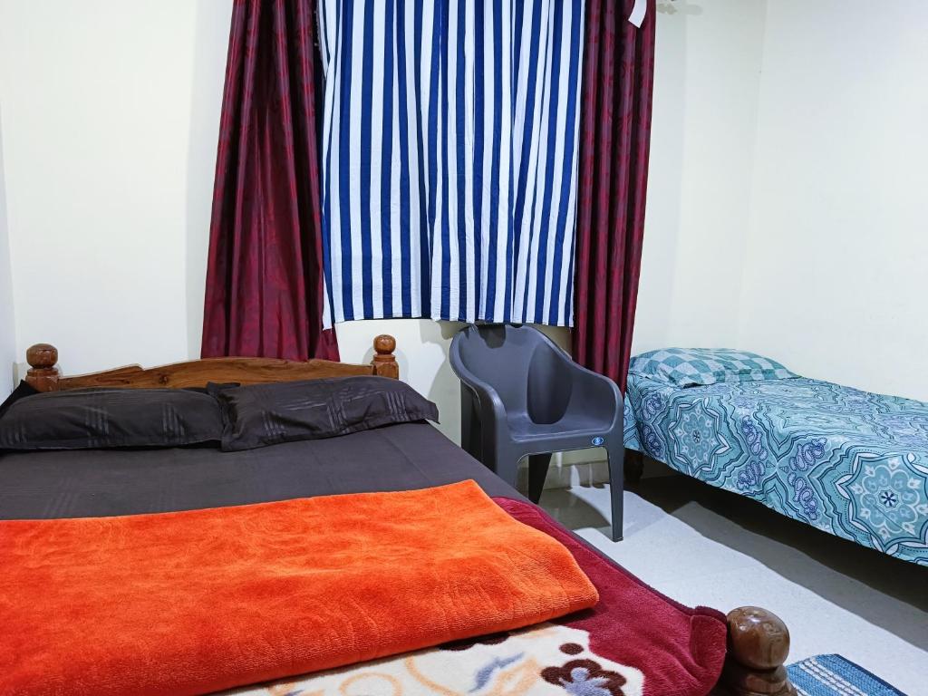 a bedroom with a bed and a chair in it at Brindavan cottage in Madikeri