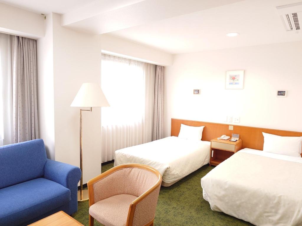 una camera d'albergo con due letti e una sedia blu di SAIDAIJI GRAND HOTEL - Vacation STAY 92844 a Okayama
