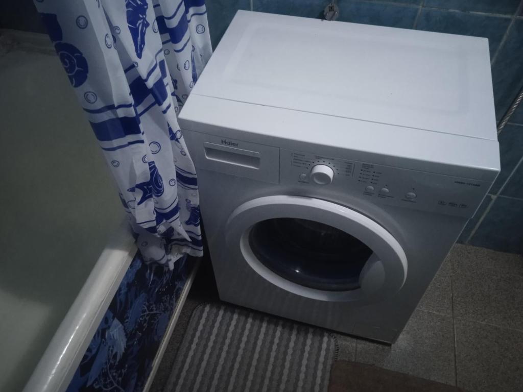 een wasmachine in een badkamer met een gordijn bij Апартаменты по ул Кайсенова in Öskemen