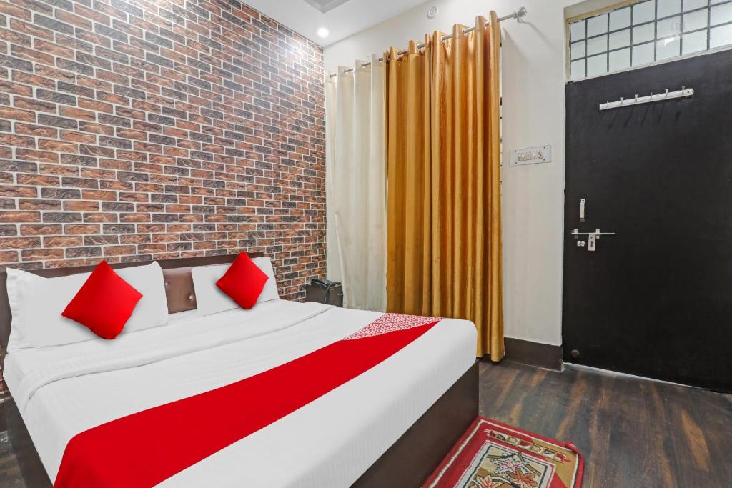una camera da letto con un letto con cuscini rossi e un muro di mattoni di OYO Flagship Hotel New Pacifica Grand Near Phoenix United Lucknow a Charbagh