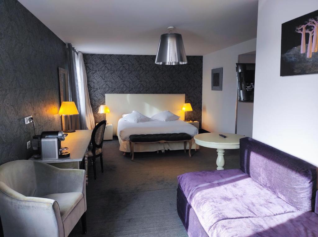 a hotel room with a bed and a table and a couch at Hôtel de Paris in Besançon