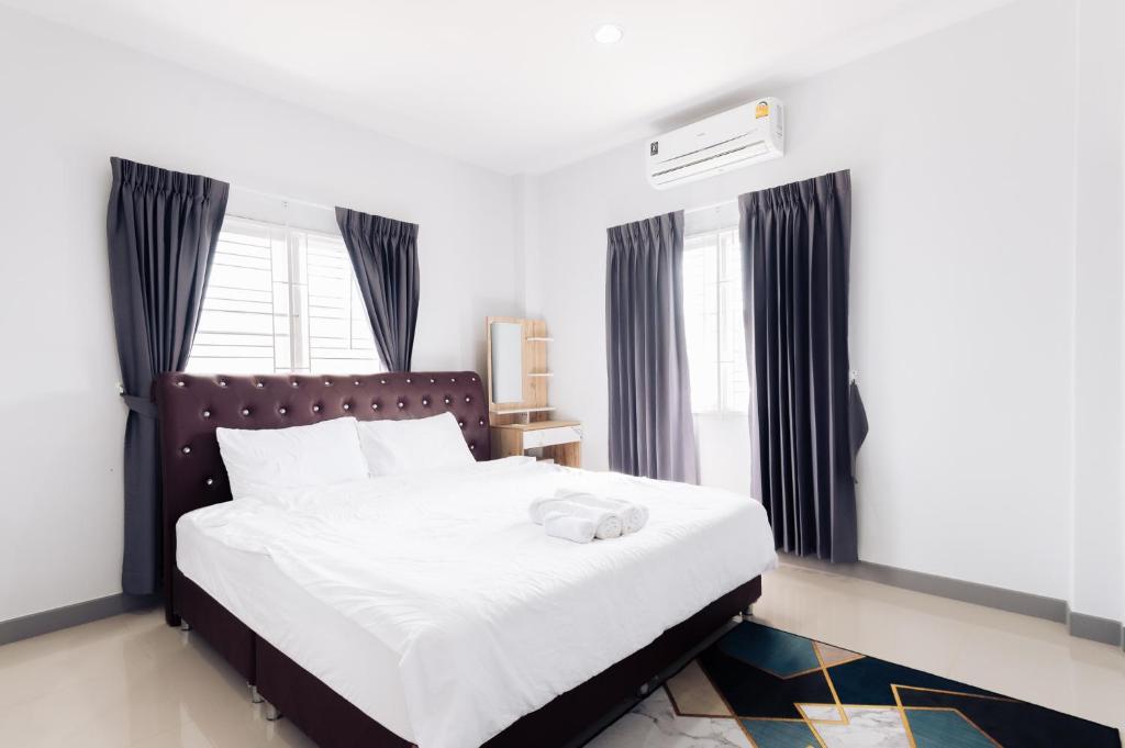 1 dormitorio con 1 cama blanca grande con cortinas negras en AABAN House 02, en Hat Yai