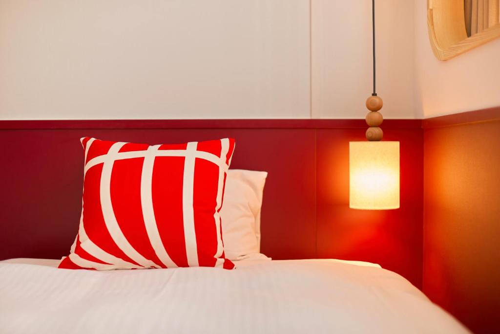 a bed with a red and white pillow and a lamp at Kyoto Tower Hotel in Kyoto