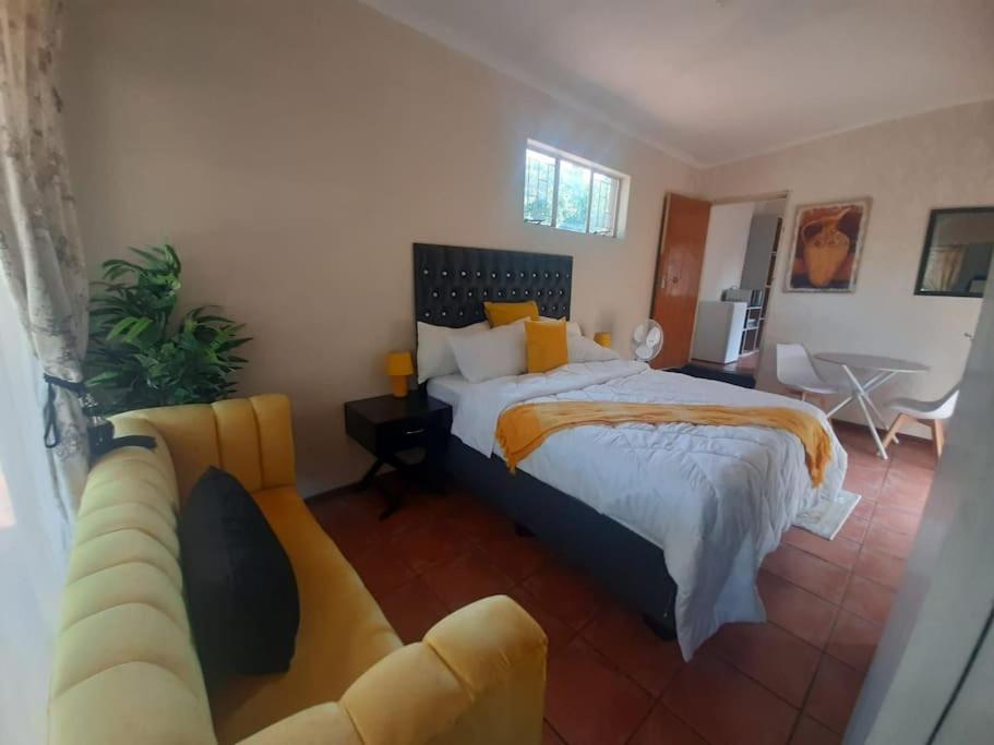 a bedroom with a king sized bed and a couch at A humble abode that is cozy in Centurion
