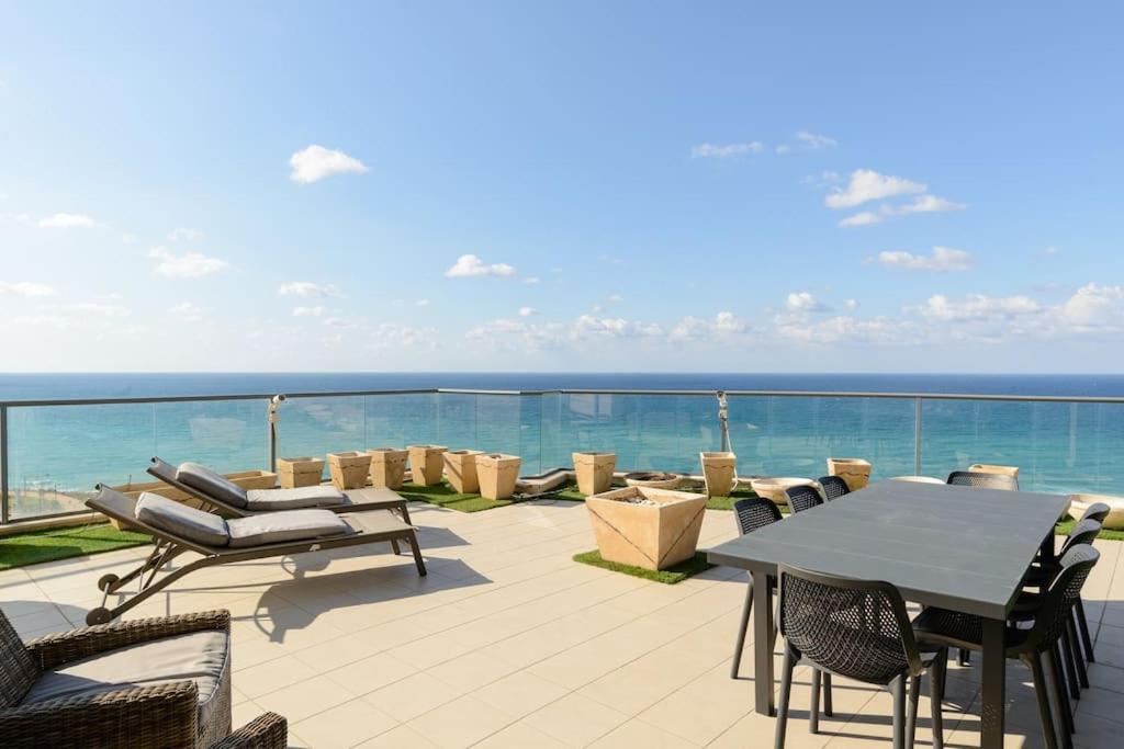 um pátio com uma mesa e cadeiras e o oceano em Jacuzzi Penthouse with wide Sea View in Natanya em Netanya