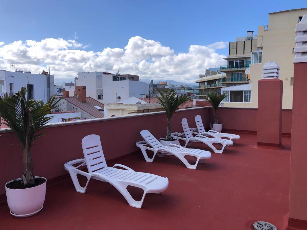 a row of white lounge chairs on a roof at Rosamar Playa de Las Canteras in Las Palmas de Gran Canaria