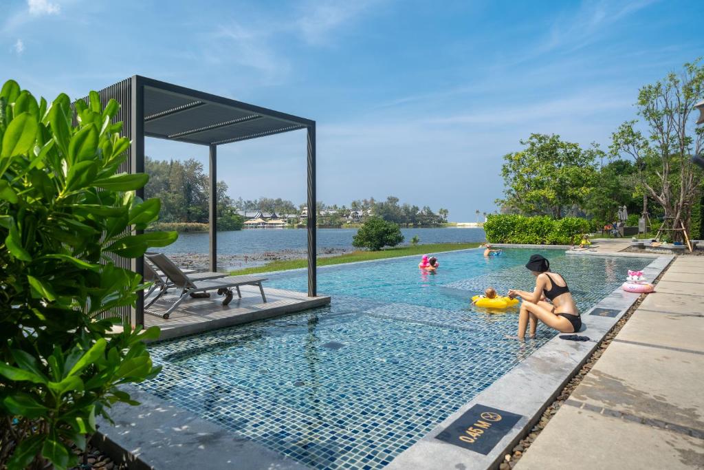 una piscina en un complejo con gente jugando en él en Лагуна Пхукет Апартаменты 2 спальни 300 метров до пляжа Бангтао, en Phuket