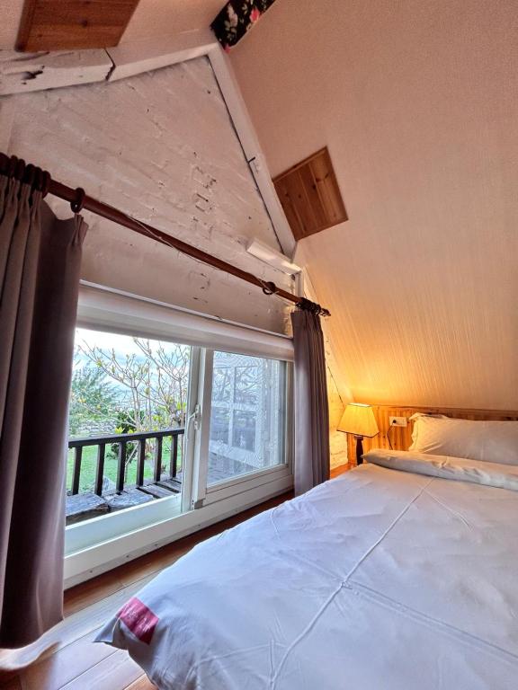 a bedroom with a bed and a large window at Bridge12th B&amp;B in Yanliau