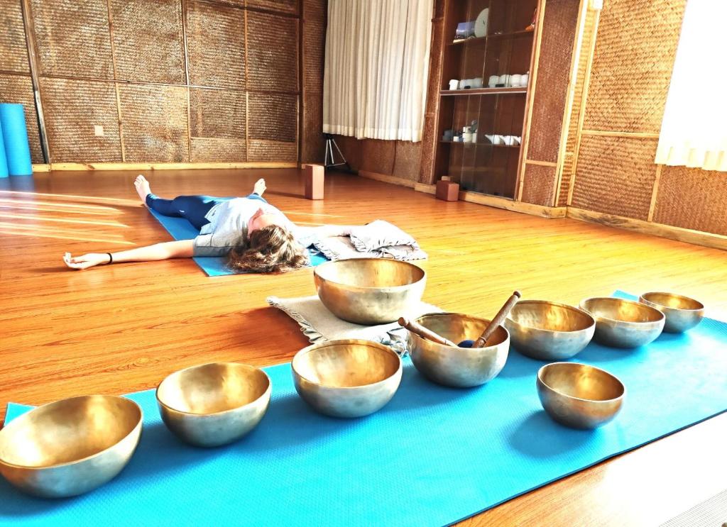 a person laying on the floor next to a bunch of bowls at Bodhidham Yoga retreat Ashram in Pokhara