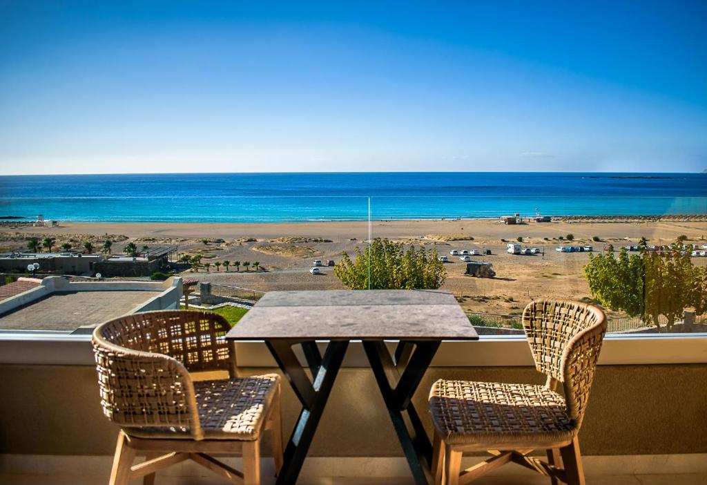 uma mesa e cadeiras numa varanda com vista para a praia em Panorama Hotel em Falasarna