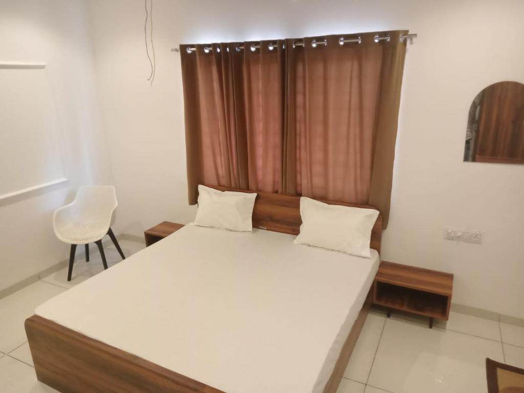 a bedroom with a large white bed with a window at Vaatsaly Rooms in Indore