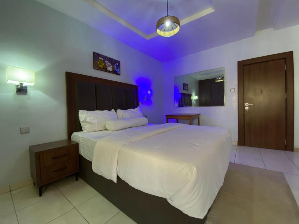 um quarto com uma cama grande e iluminação roxa em Gimbiya street NNPC estate em Abuja