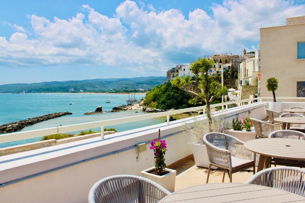 Hotel Punta San Francesco في فييستي: شرفة مع طاولات وكراسي وإطلالة على المحيط