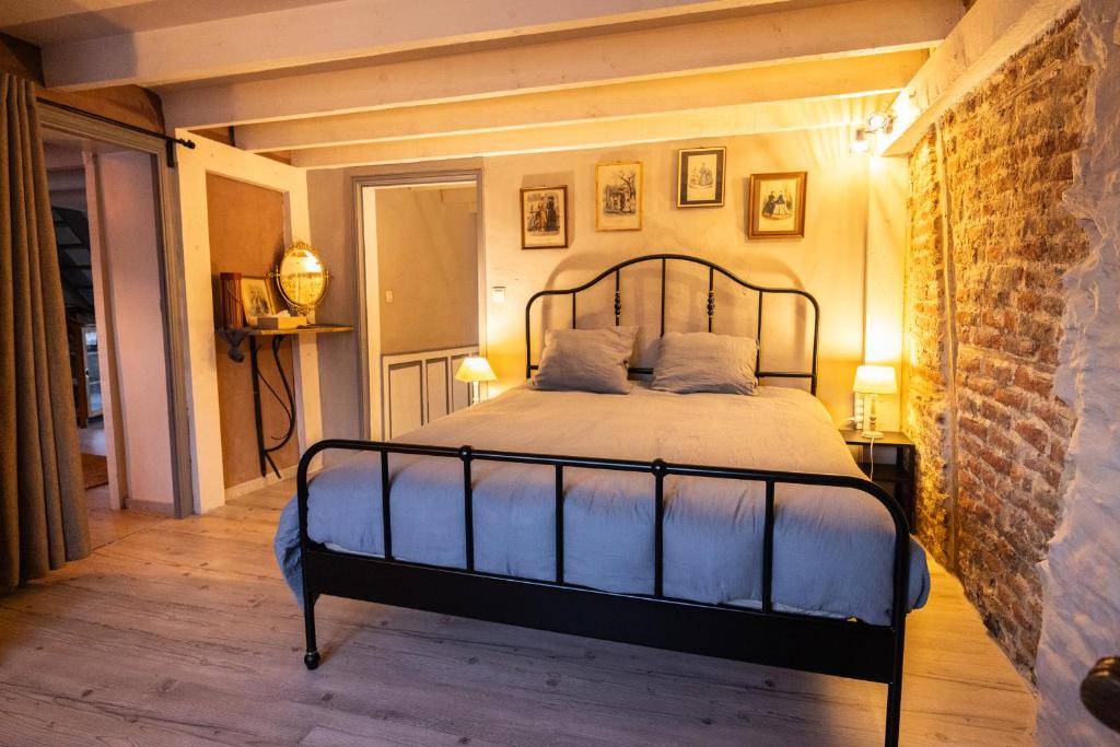 ein Schlafzimmer mit einem Bett und einer Ziegelwand in der Unterkunft Le Relais de la Maillère in Dalhem