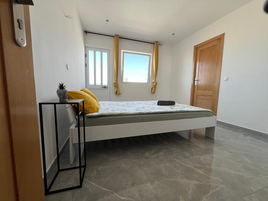a small bed in a room with two windows at Brand new apartment in Mindelo in Mindelo