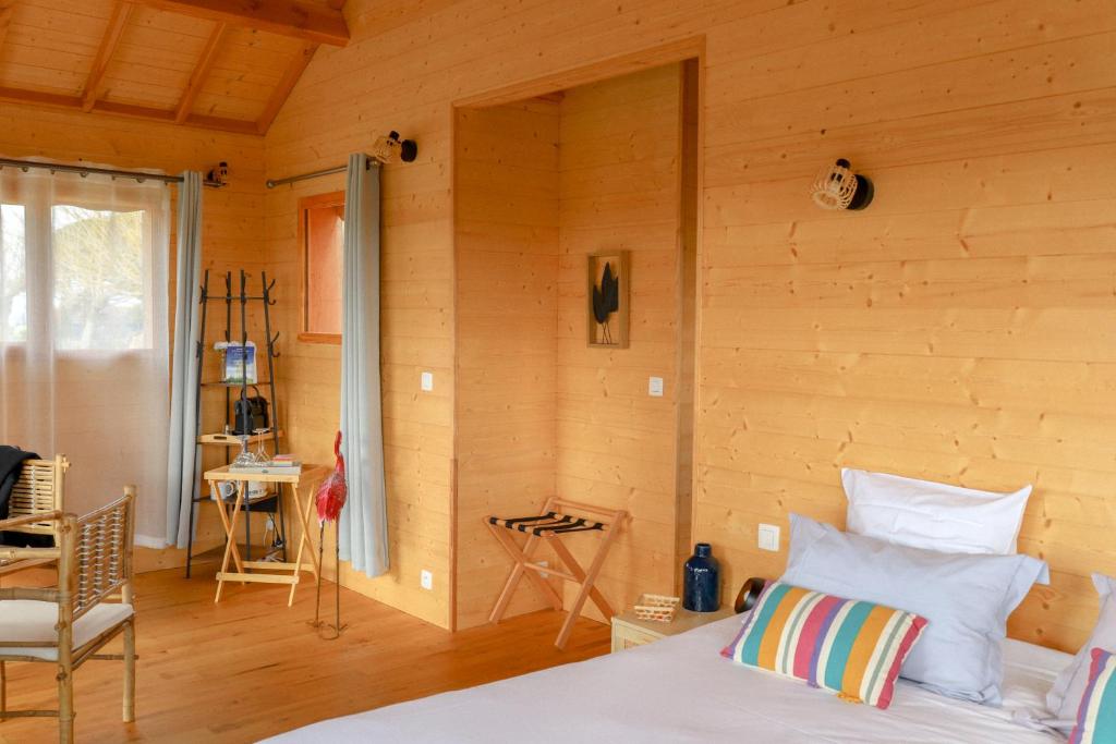 1 dormitorio con 1 cama y pared de madera en Le Domaine de La Tour des Vents, en Bergerac