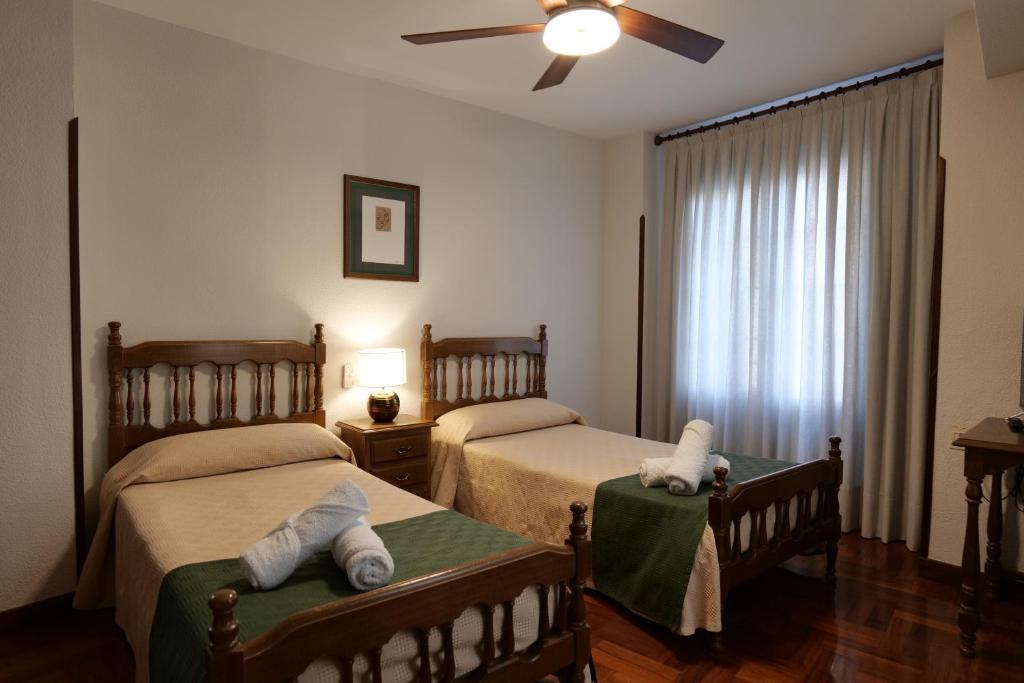 a bedroom with two beds and a ceiling fan at Hostal Cristina in Estella