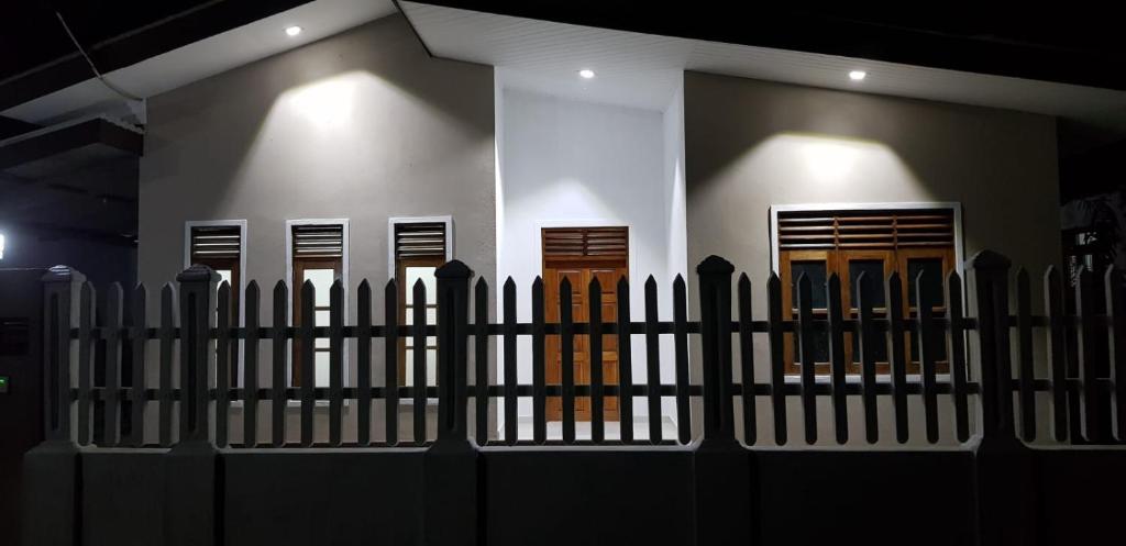 uma cerca em frente a um edifício com portas castanhas em Archie Homes em Kadawata