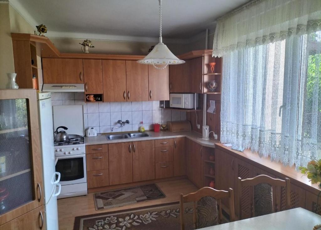 una cocina con armarios de madera y electrodomésticos blancos en Dom jednorodzinny, en Łapy