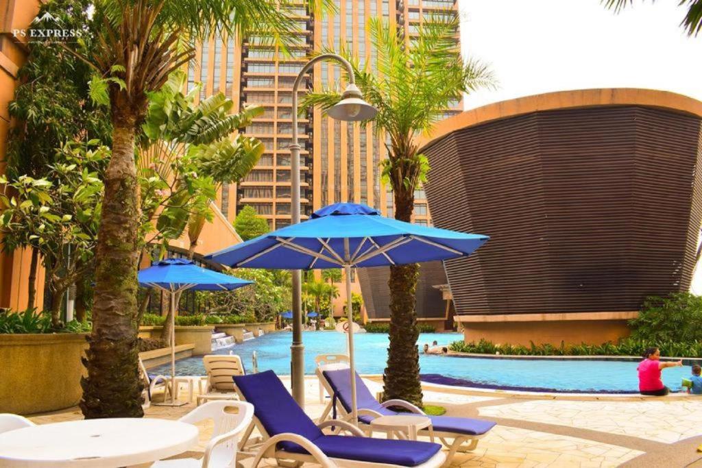 uma piscina com cadeiras e guarda-sóis e uma piscina em Urban Suite Times Square Kuala Lumpur em Kuala Lumpur
