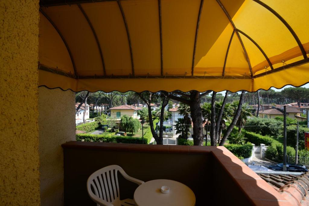 a table and a chair on a balcony with an umbrella at Hotel Giulio Cesare in Cinquale